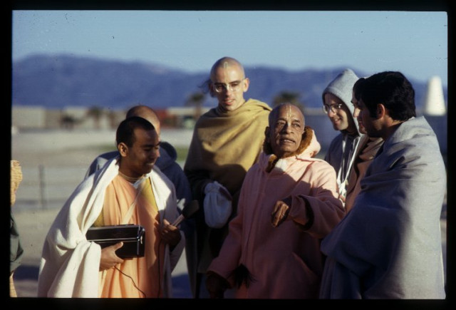 Шрилу Прабхупаду сопровождают д-р Сингх и другие ученики.